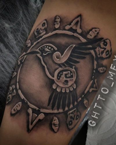 Black and grey Aztec sun stone medallion with a hummingbird carved in relief on skin