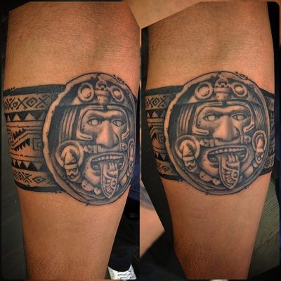 Aztec sun stone medallion in black and grey set into a solid tribal band wrapping the leg.