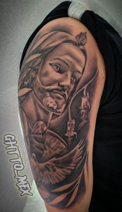 Black and grey upper arm tattoo of a bearded saint holding a candle with a dove below