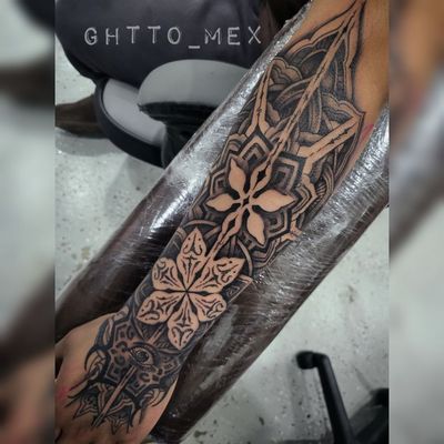 Bold blackwork ornamental sleeve running down a forearm onto the hand, mandalas and negative space flowers