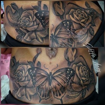 Large black and grey butterfly flanked by roses and a coiled snake spanning a stomach