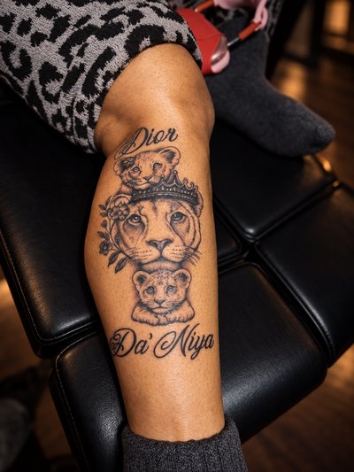 Black and grey crowned lioness with two cubs, flowers and script on the calf
