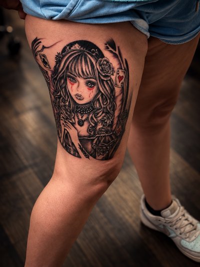 Black and grey illustrated woman with roses, playing cards and red accents on the thigh