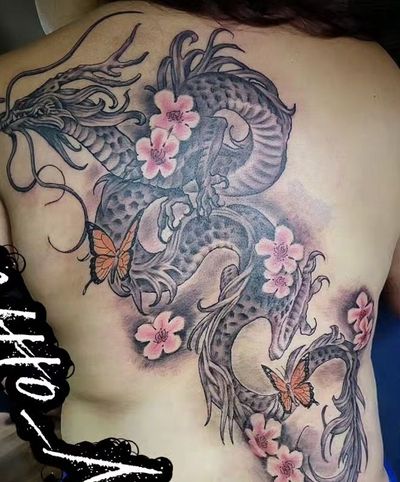 Full back piece of a black and grey dragon with pink cherry blossoms and orange butterflies.