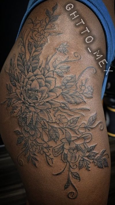 Fine line black and grey floral tattoo of peonies, lilies and trailing vines across a hip and thigh