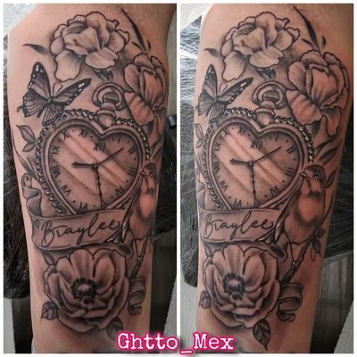 Heart shaped pocket watch surrounded by roses, a butterfly, a robin and a script name banner on a forearm