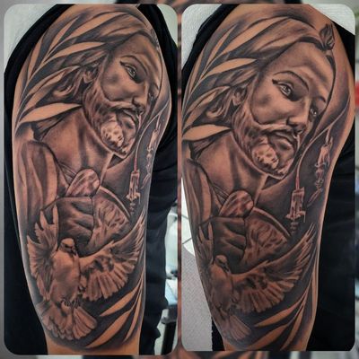 Black and grey Jesus face framed by palm leaves above a dove with spread wings and lit candles