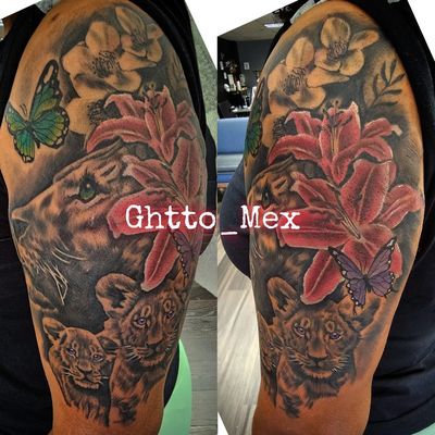 Color upper arm tattoo of a lioness and two cubs with pink lilies and green and purple butterflies.