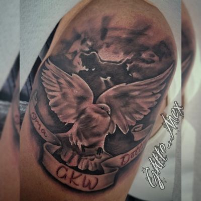 Upper arm tattoo of a dove in flight over clouds with a name banner in red lettering