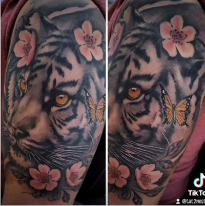 Color realism tiger head with pink cherry blossoms and a monarch butterfly on an upper arm