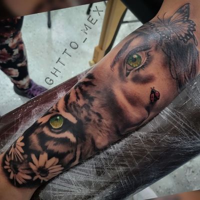 Forearm sleeve blending a woman's green eye with a tiger face, sunflowers and a small ladybug